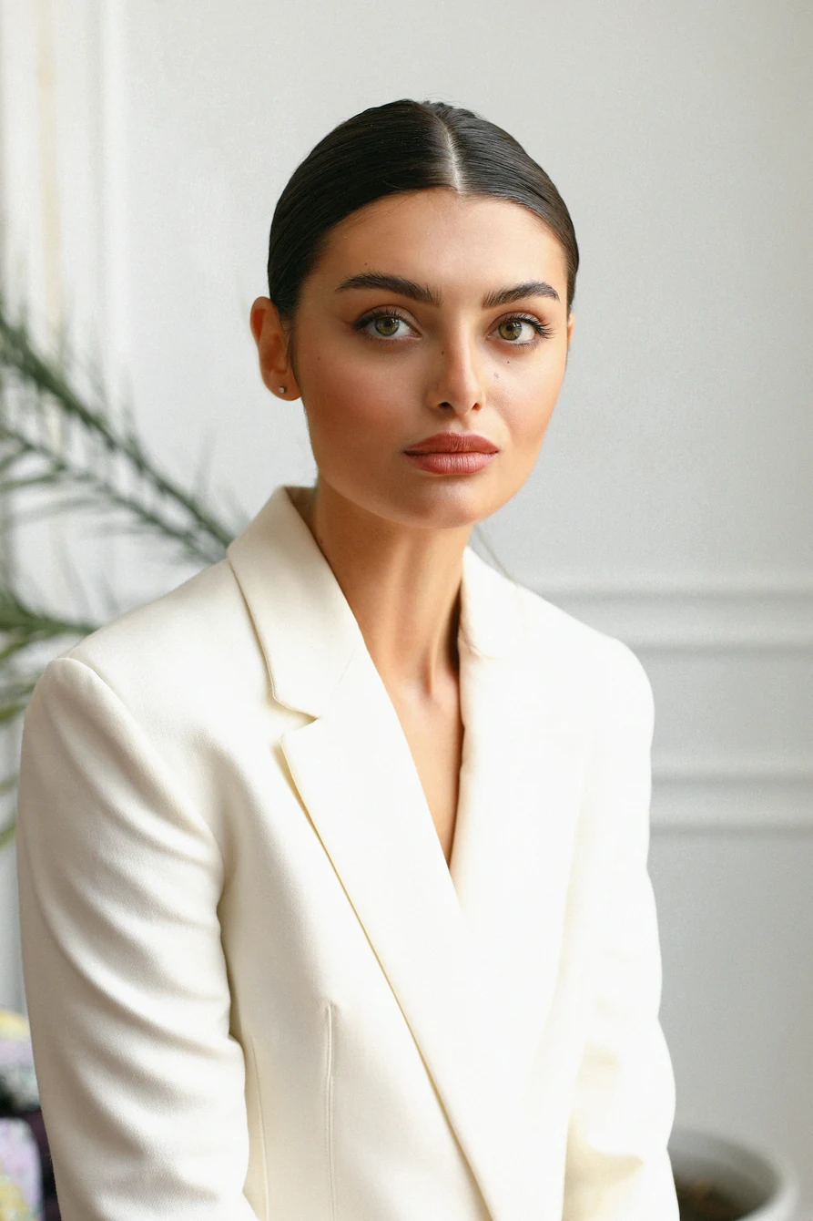 Model im weißen Blazer vor hellem Interieur